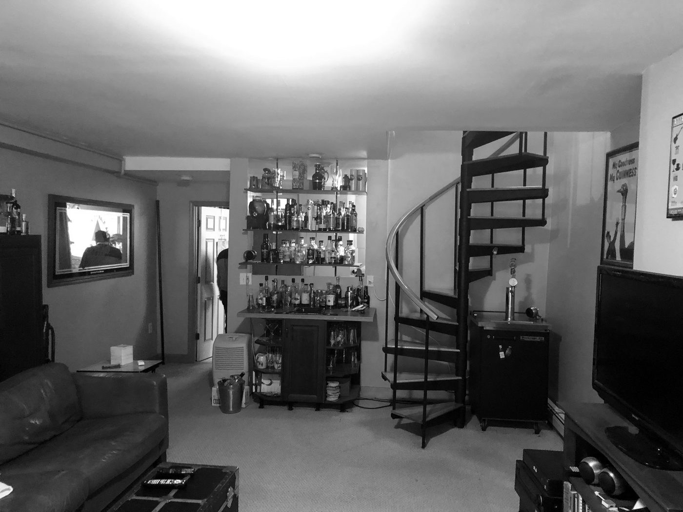 Dark basement rec room with spiral stair before renovation